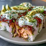 Golden, bubbly Spicy Salmon Sushi Bake topped with sesame seeds and avocado, served warm with roasted seaweed snacks for a deconstructed sushi experience.
