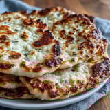 Golden-brown Easy Garlic Naan Bread fresh from the skillet, with bubbly texture and a buttery garlic sheen ideal for wrapping grilled meats.