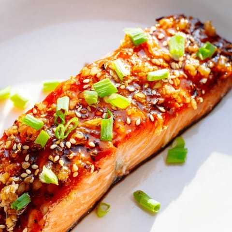 Cooked honey garlic salmon fillets sizzling in a pan, infused with savory sauce and garlic aroma.