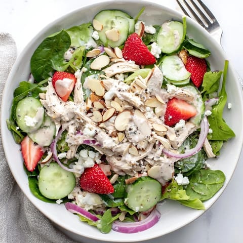 Vibrant mixed greens topped with tender chicken, bright strawberries, crumbled feta, and toasted almonds make this Strawberry Poppy Seed Chicken Salad a refreshing main course.