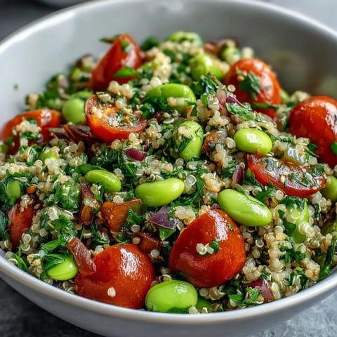 A vibrant bowl of Edamame and Quinoa Salad with cherry tomatoes, cucumber, and fresh herbs tossed in zesty citrus dressing.