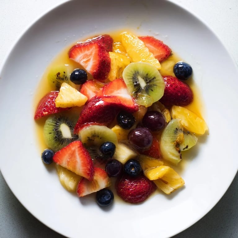 Freshly prepared fruit salad featuring a medley of summer fruits, tossed with tangy citrus glaze.