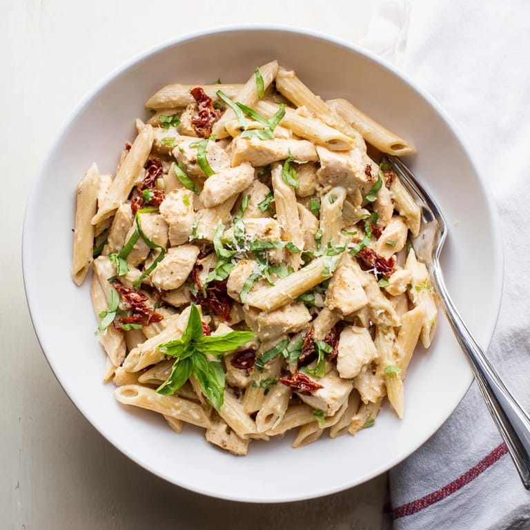 Close-up of Creamy Sun-Dried Tomato Chicken Pasta, where tender penne and savory chicken meet sun-dried tomatoes in a luscious, cream-coated Italian-American comfort dish.