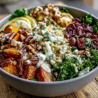 Roasted sweet potatoes and fluffed quinoa in a Harvest Kale Quinoa Bowl, drizzled with creamy lemon tahini dressing.