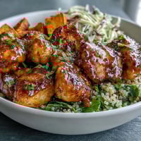Golden spiced chicken, caramelized sweet potatoes, and fluffy quinoa layered in a vibrant Hot Honey Chicken Bowl, topped with crunchy red cabbage slaw and drizzled with tangy hot honey mustard dressing.